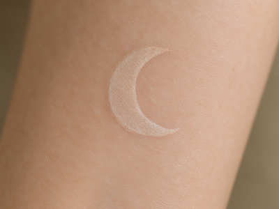 Close-up of a healed white ink crescent moon tattoo showing its faded, subtle appearance on skin